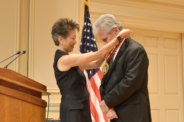 Jane Chu puts Heritage medal around the neck of Billy McComiskey as he bows his head