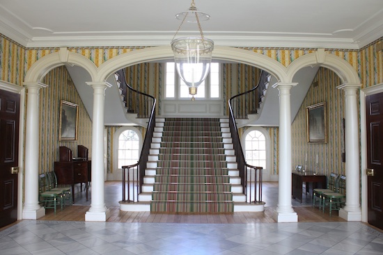 A large entry hall with a central staircase that branches off to the left and right after the first flight of stairs