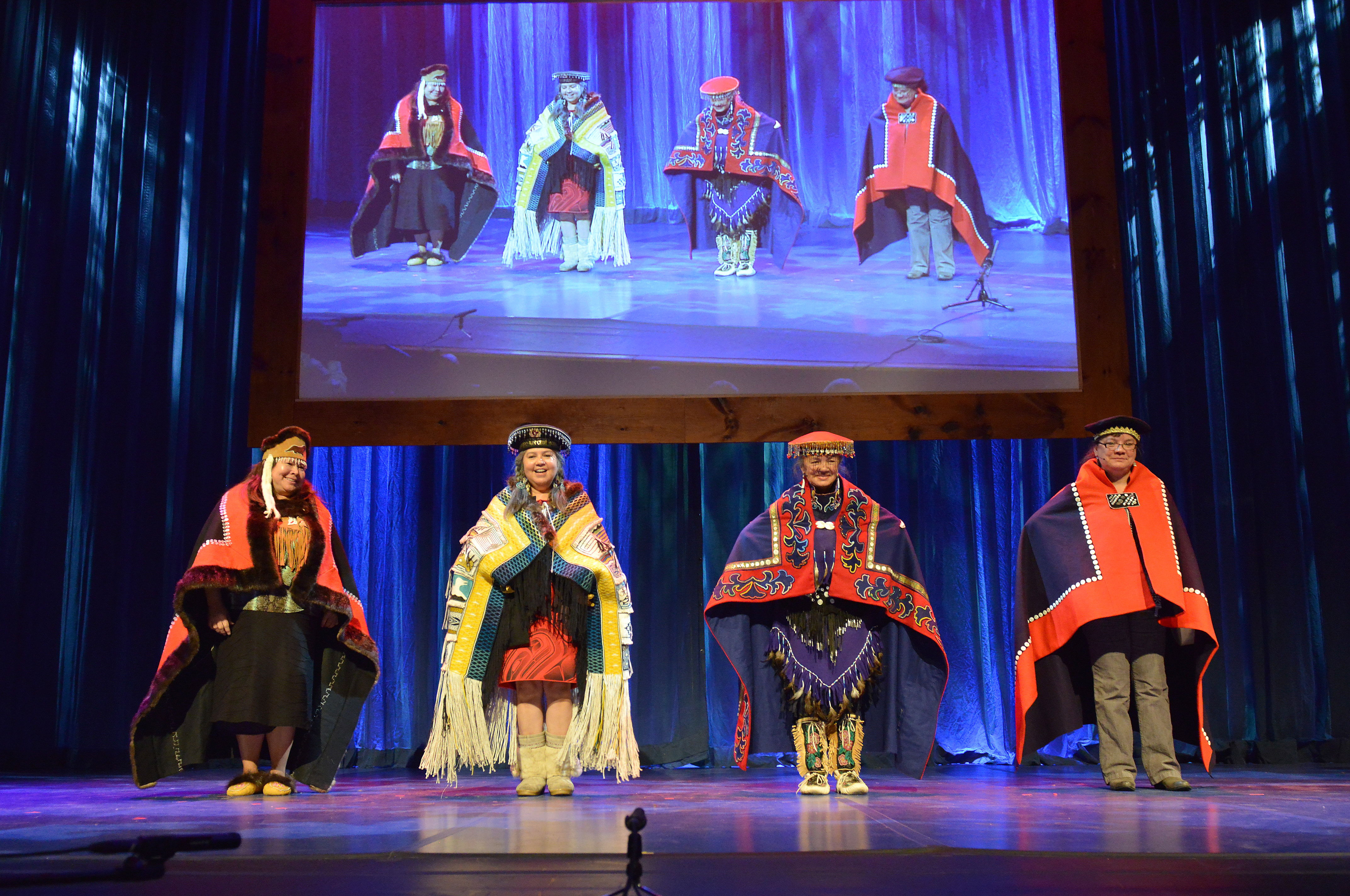 Four women on stage standing with heavy traditional attire.