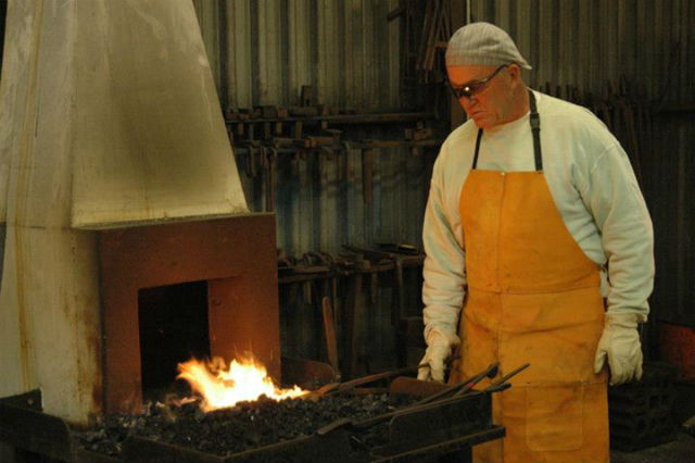 An artist working at a blacksmithing coal forge