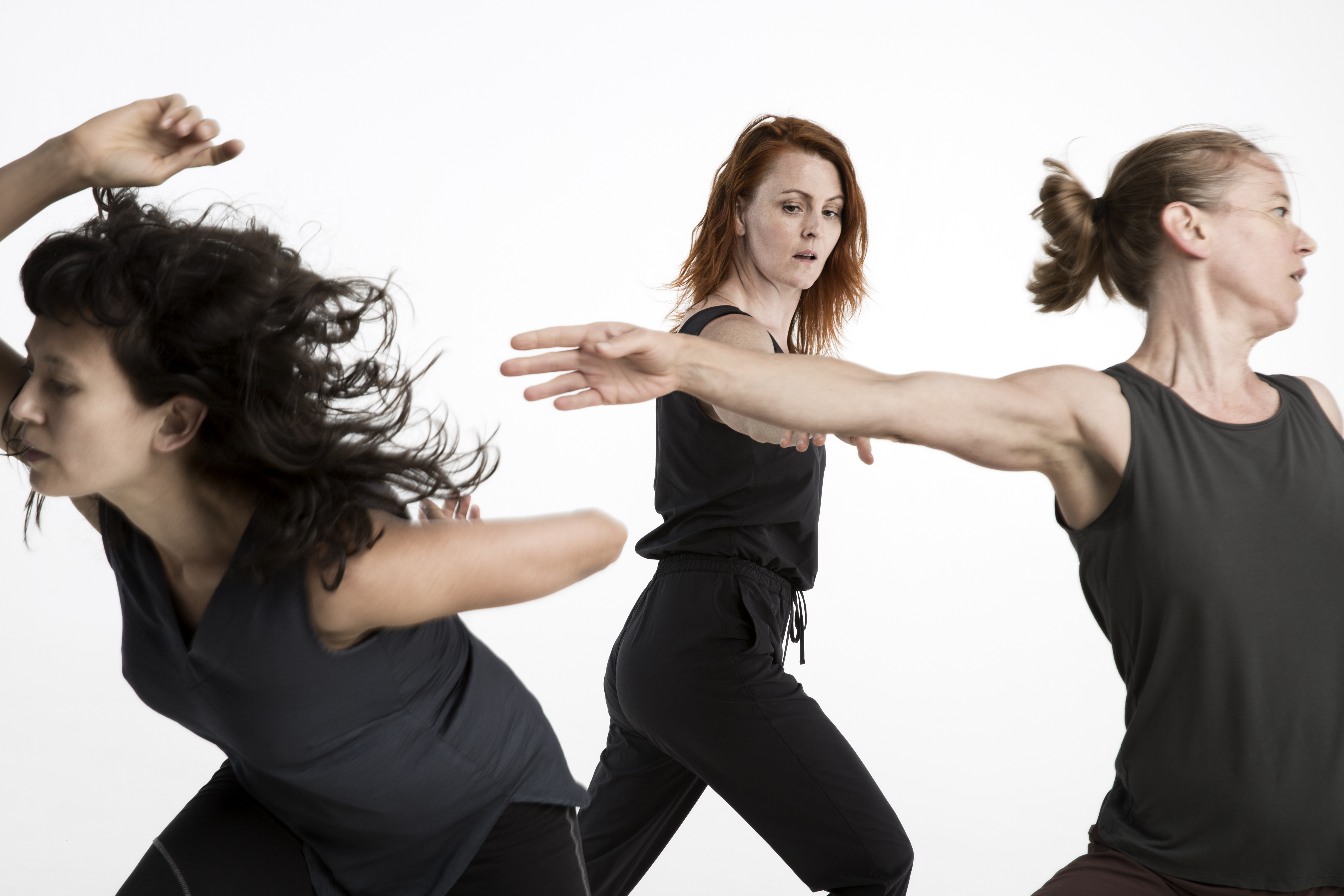 Three women wearing black dancing in different directions. 
