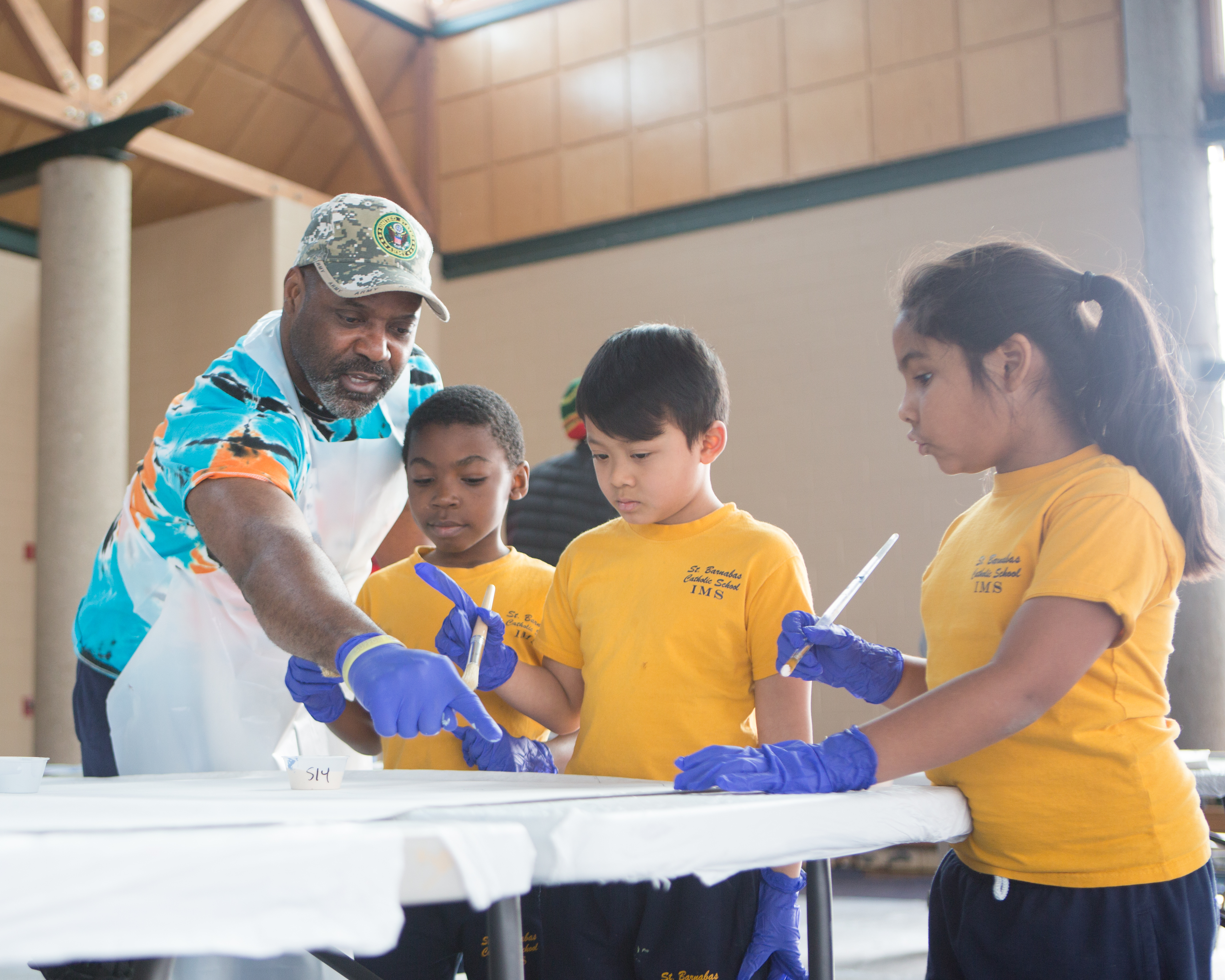 A man helps young children complete a group painting