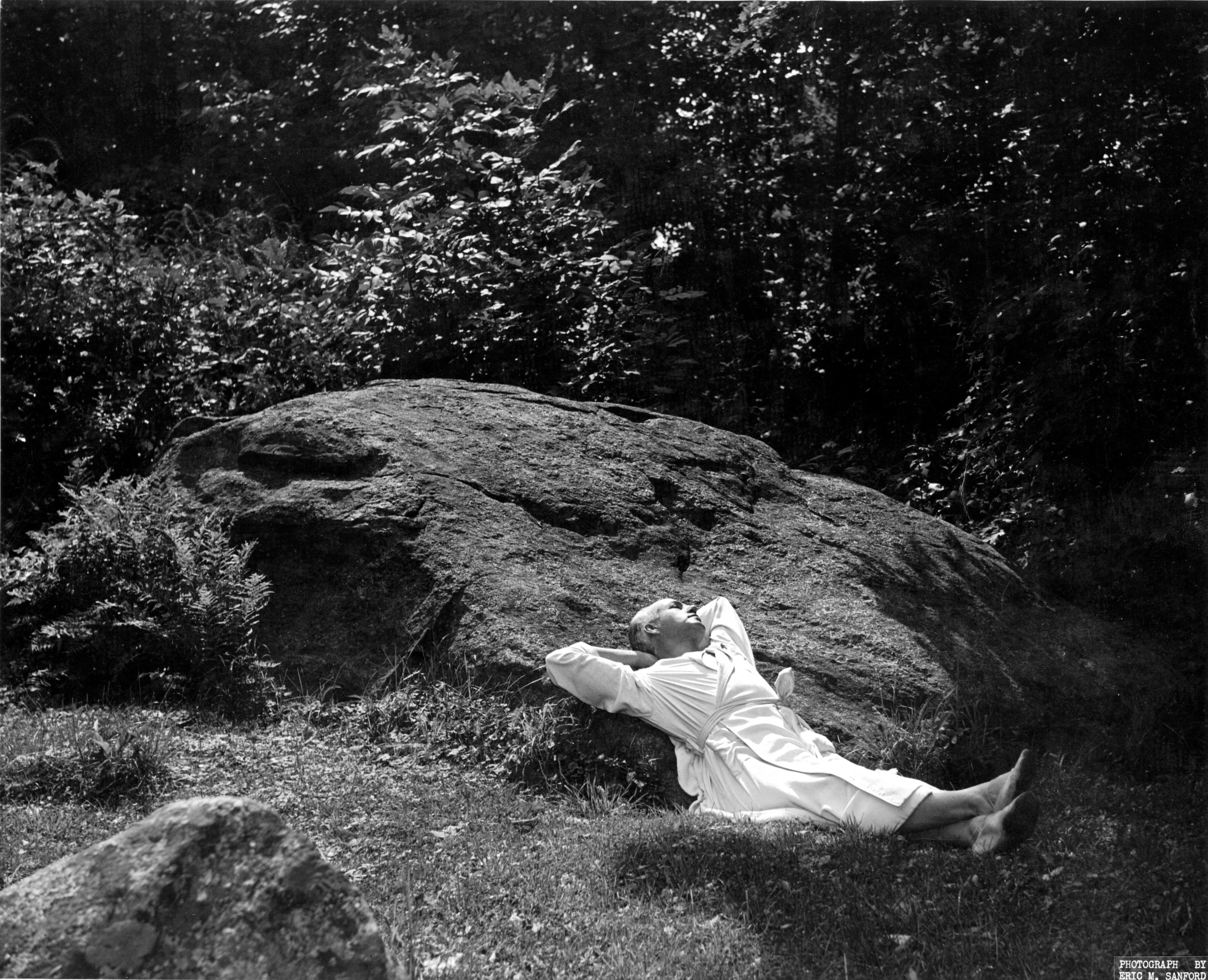 Man in robe lying against a giant rock. 