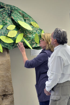 A man and woman look at a tree made of paper