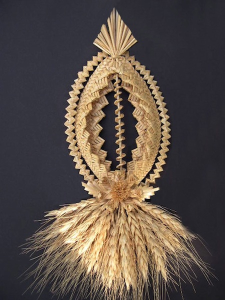 a braided straw artwork with a spheroid shape up town and straw tassels