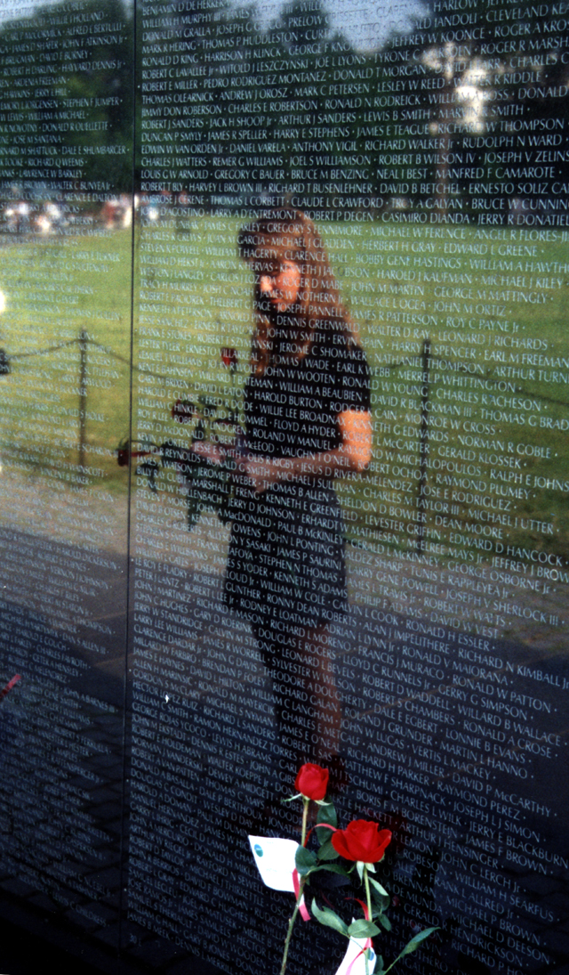 Women&#039;s reflection in front of black wall with white writing, the Vietnam Veterans Memorial