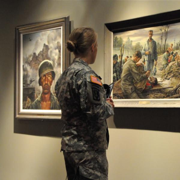 Woman in military uniform looking at art in museum. 