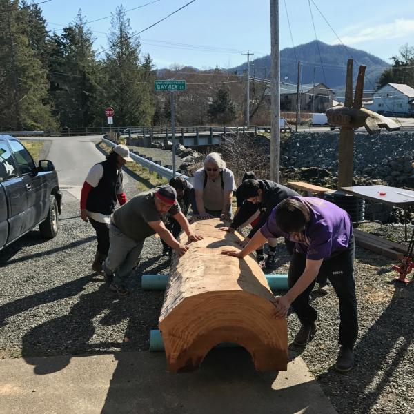 Men transfer a large cut log