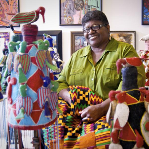 African-American woman surrounded by quilts.