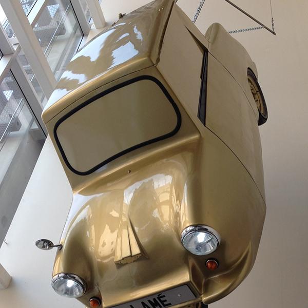 Gold car hanging from ceiling in museum.