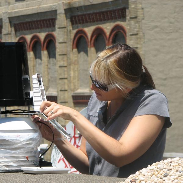 Woman in sunglasses putting together a piece of equipment.