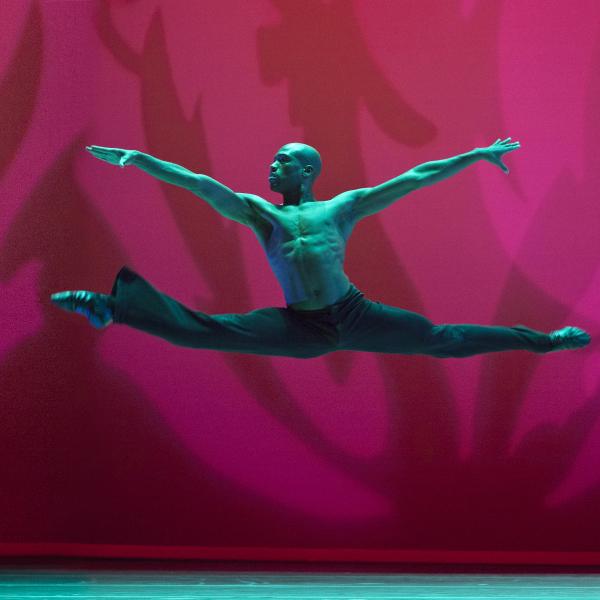 Man in mid-air with arms and legs extended during dance move. 