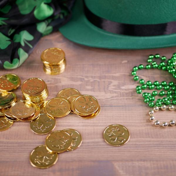 Photo with gold coins, green party beads, a green hat, and black scarf with green four-leaf clovers