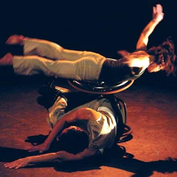 An able bodied dancer laying across a wheechair dancer