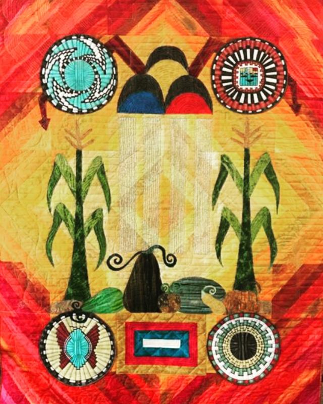 A colorful red, yellow, green, and blue quilt showing crops and Hopi symbols