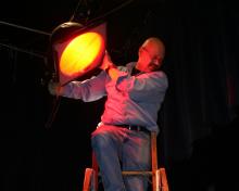 Man on ladder adjusting spotlight. 