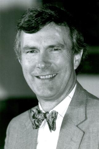 Portrait of white man with short dark hair wearing a suit and bowtie. 