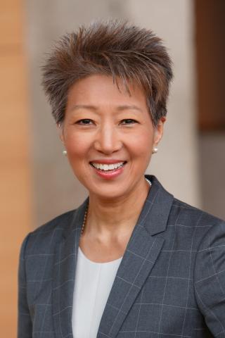 Portrait of Asian woman with short dark hair wearing a white shirt and blue blazer