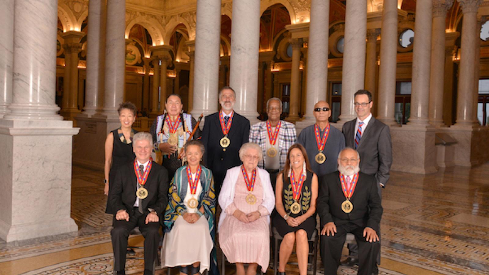 a group photo of the 2016 NEA National Heritage Fellows with Jane Chu and Cliff Murphy on the colonnaded mezzanine at the Library of Congress Jefferson building
