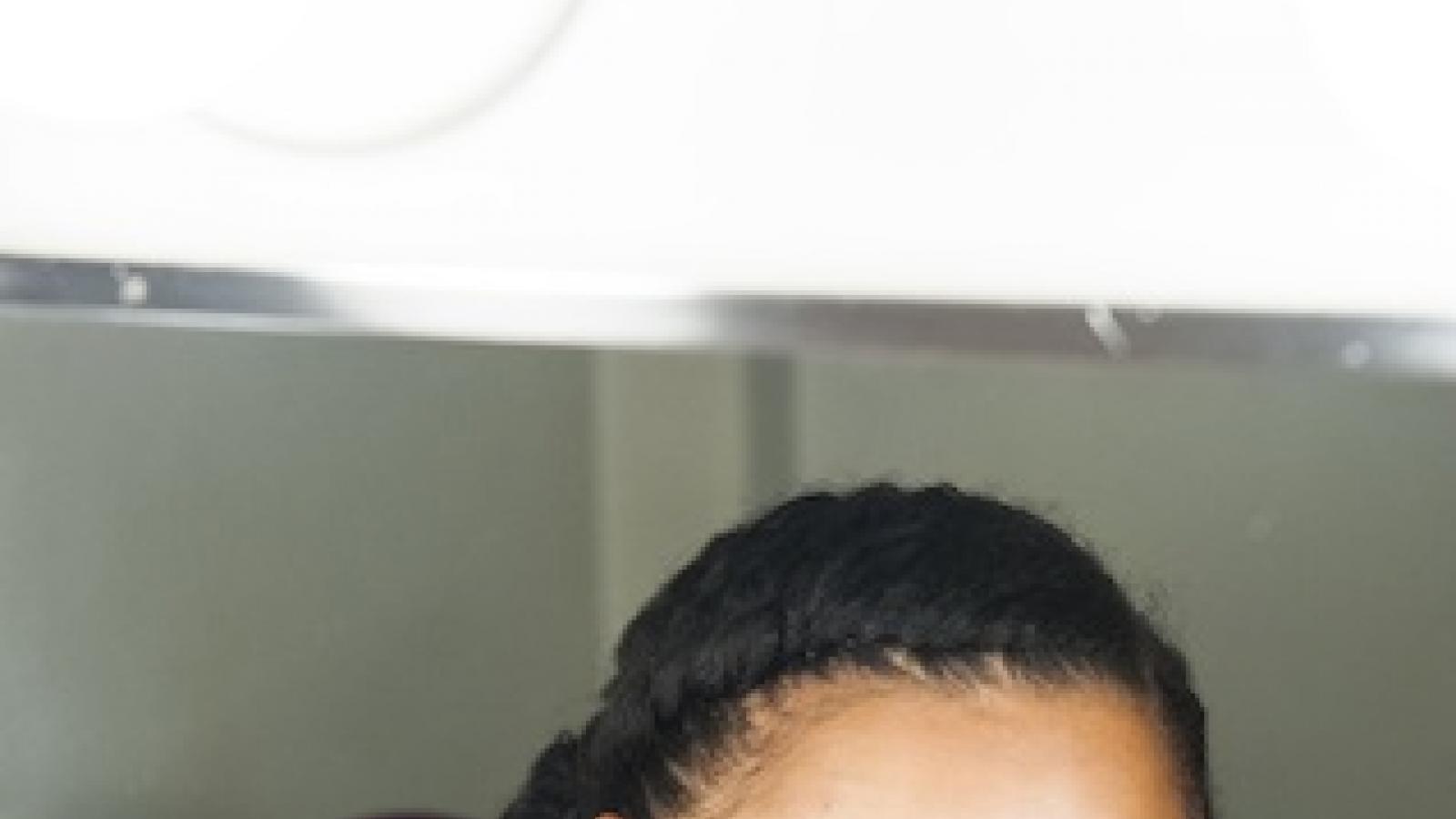 A young black woman looks sideways and is reflected in a dressing room mirror