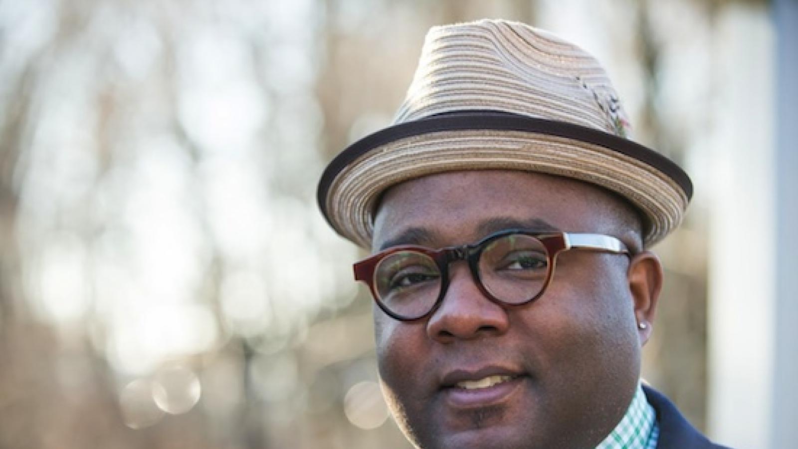 an African American man in glasses and a small straw fedora