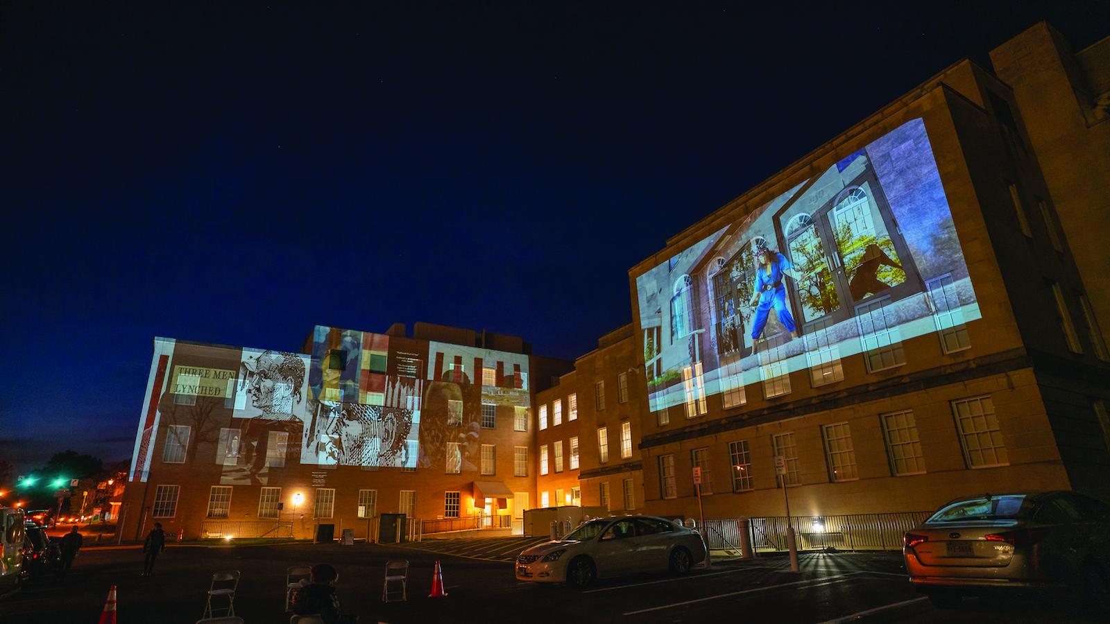 Projections of artwork on the sides of two buildings. 