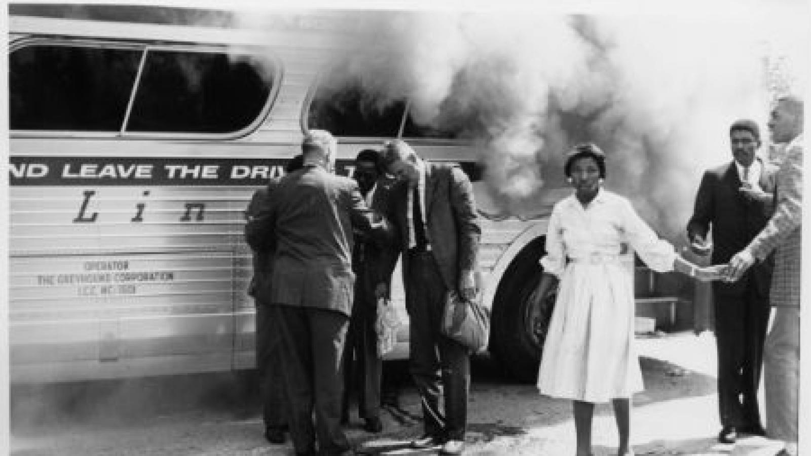 Freedom Riders gather with authorities alongside their burning bus after a mob attack outside Anniston, Alabama. Photo courtesy of Firelight Media