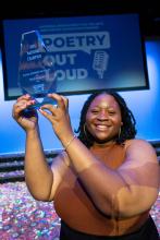 Niveah Glover, a young Black woman, holding her Poetry Out Loud National Champion trophy aloft