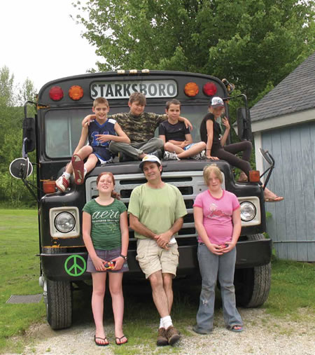 Artist-in-residence Matthew Perry (center) with children from Starksboro’s Hillside Manor Mobile Home Park in front of Perry’s Art Bus, which he used to travel around the rural community