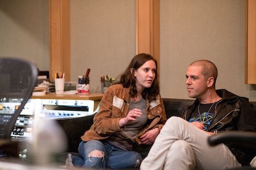 a young woman sitting next to an older man on a couch talking