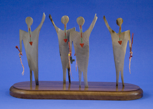 metal sculpture of four dancers with ceremonial pipes and arrow-shaped necklaces