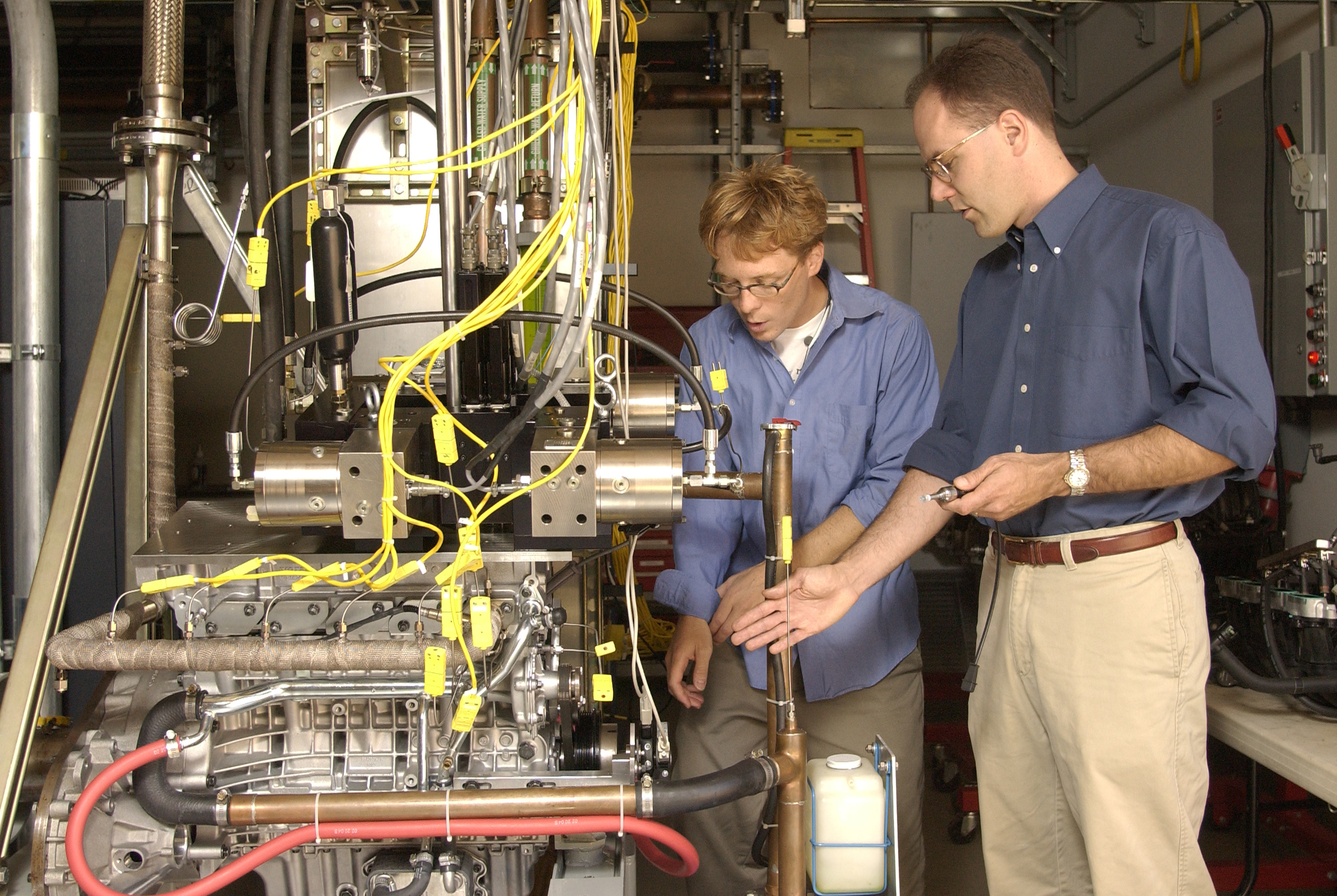 Two men looking over a car engine in a laboratory. 