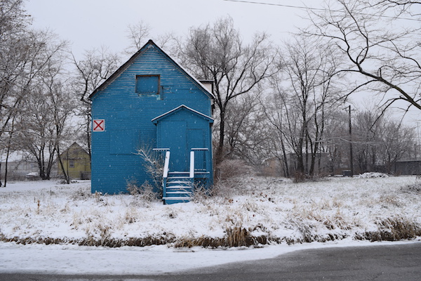 an abandoned house painted ultrasheen blue sited on a snowy field