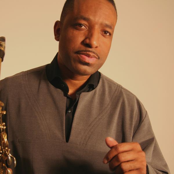 Black man holding a saxophone in his right hand. 