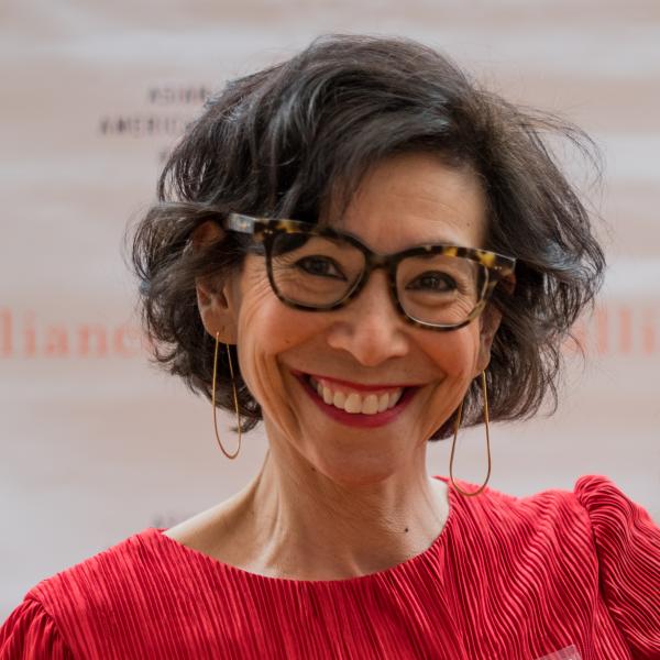 Portrait of Asian woman with short black hair, wearing glasses and a red shirt. 