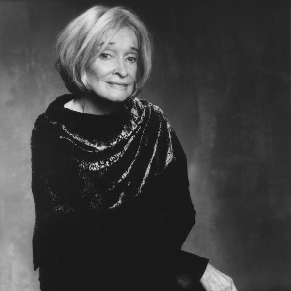 Older woman with blonde-gray hair wearing a black dress with scarf in portrait