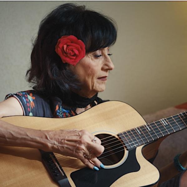 Rosie Flores seated at home playing guitar