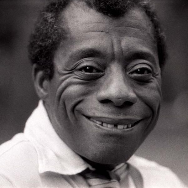 Black and white photo of a Black man wearing a white shirt and smiling. 
