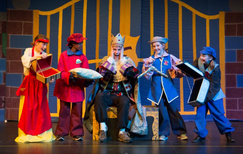 Children in costumes on stage portraying an emperor and his people. 