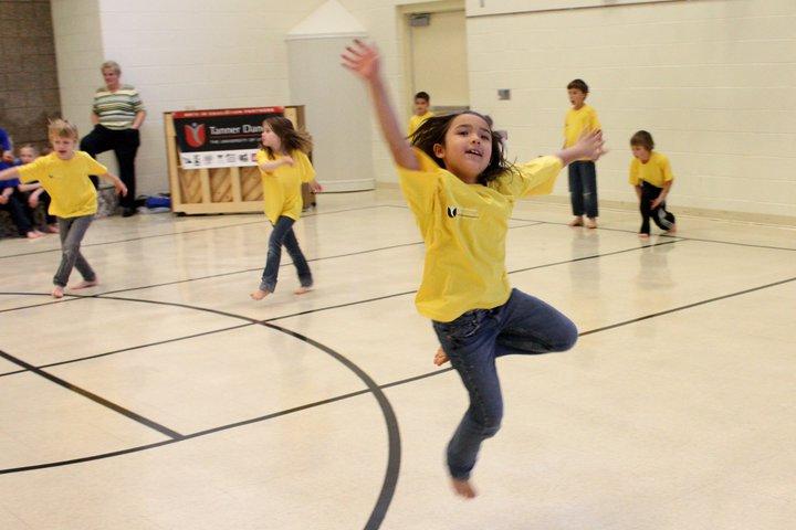 Children wearing t shirts dance in a school recreation room