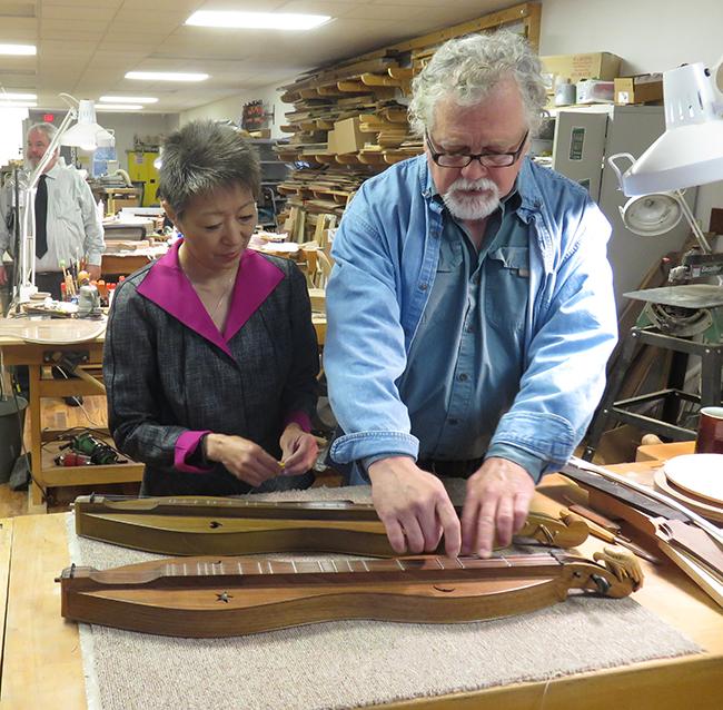 Man and woman examine a dulcimer