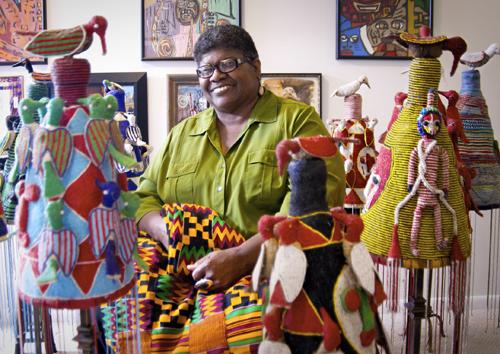 African-American woman surrounded by quilts.