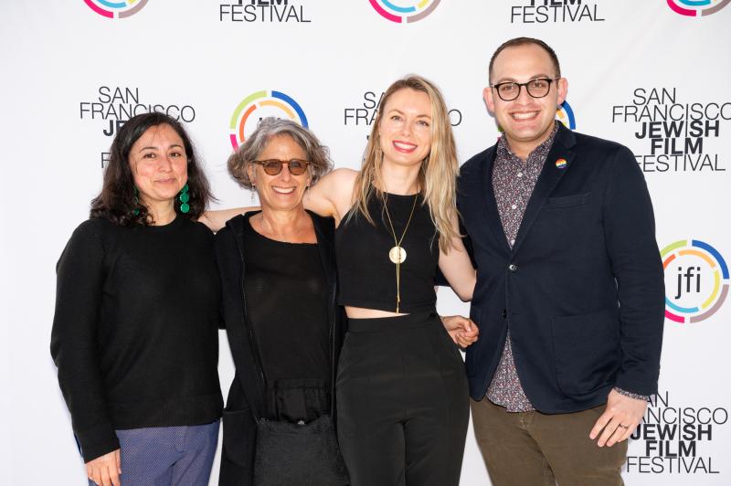 From left to right: three women and one man stand in front of a step-and-repeat that has “SAN FRANCISCO JEWISH FILM FESTIVAL” and “JFI” written in various places.
