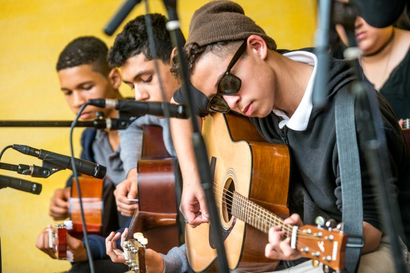 Three young men play guitars