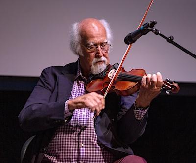 A man sits playing the fiddle