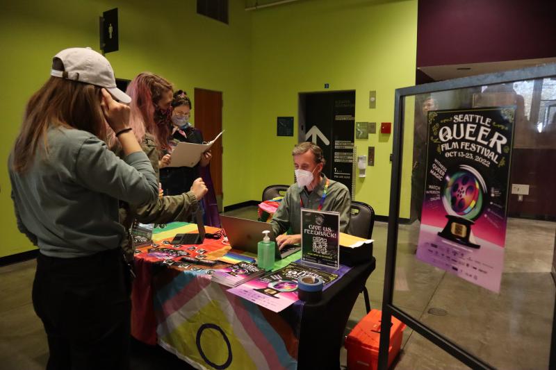 a group of people buying tickets from someone behind a table