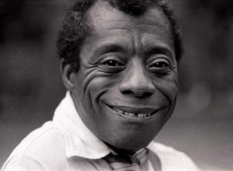 Black and white photo of a Black man wearing a white shirt and smiling. 