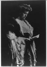 Author Edith Wharton standing and holding a book