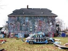 A house covered with colorful polka dots with colorful sculptures made from trash in the front yard
