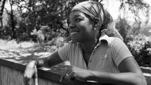 Maya Angelou poses casually leaning over the top of a fence